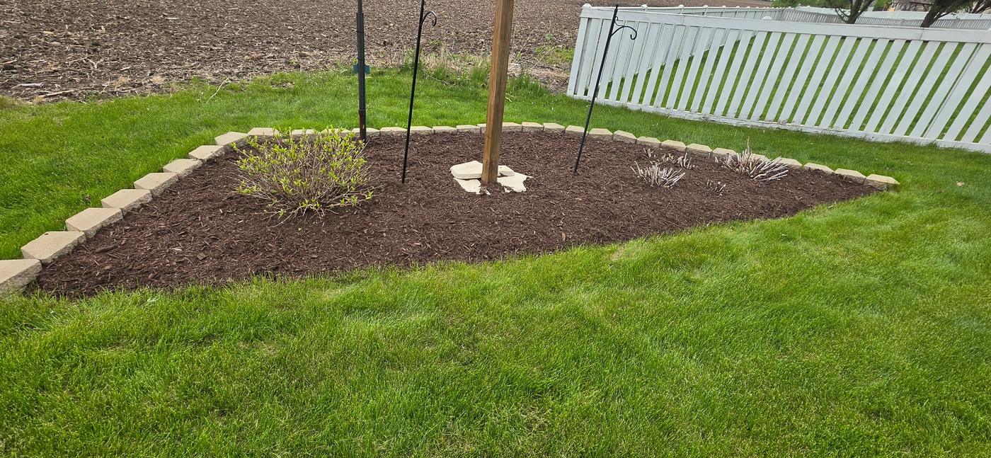 The same stone-bordered bed finished with even, fresh mulch